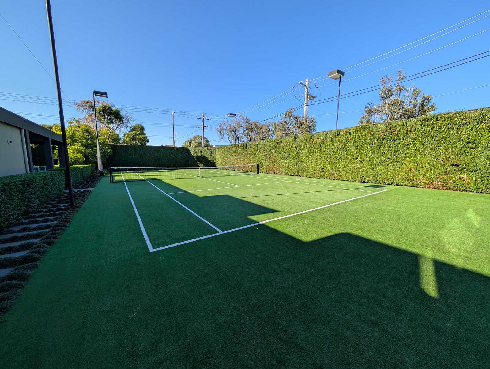 Artificial turf court with trimmed hedge